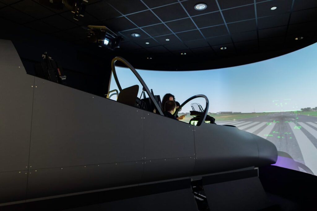 A female pilot operates a flight simulator in an advanced training facility.